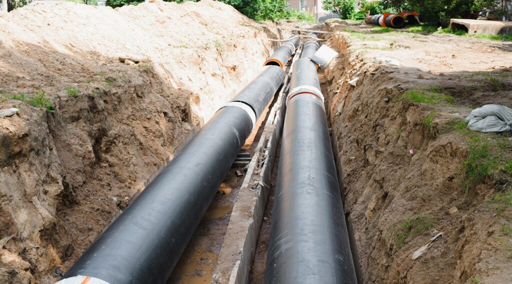 Plumbing repair. Installation of new industrial street water pipes in dug hole in two lines, outdoors
